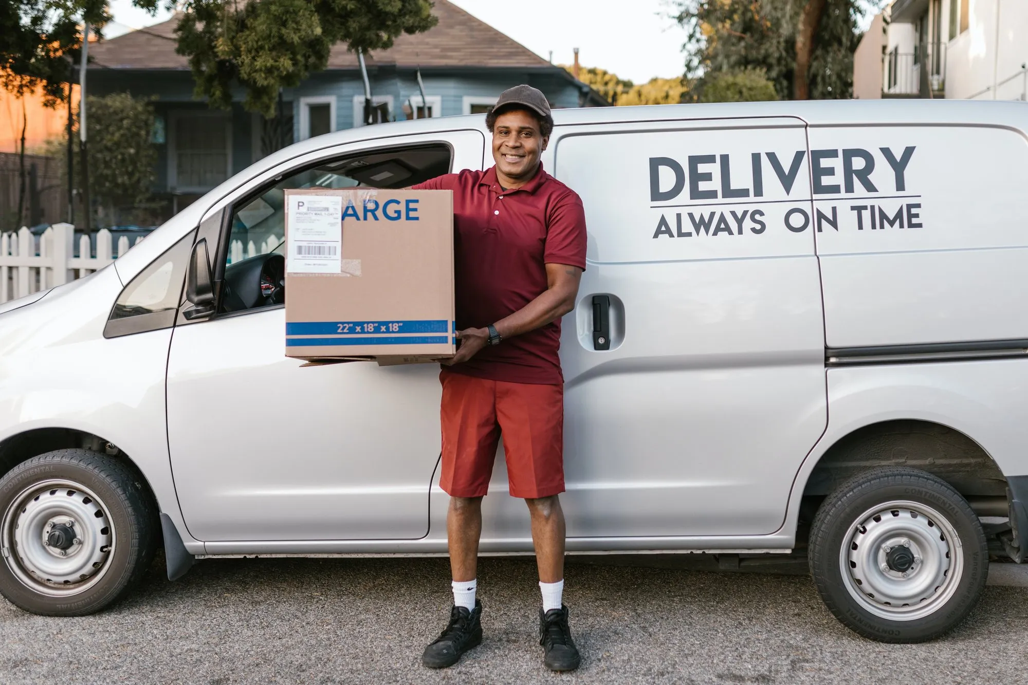 Delivery driver holding a parcel beside a white van marked ‘Delivery, always on time’